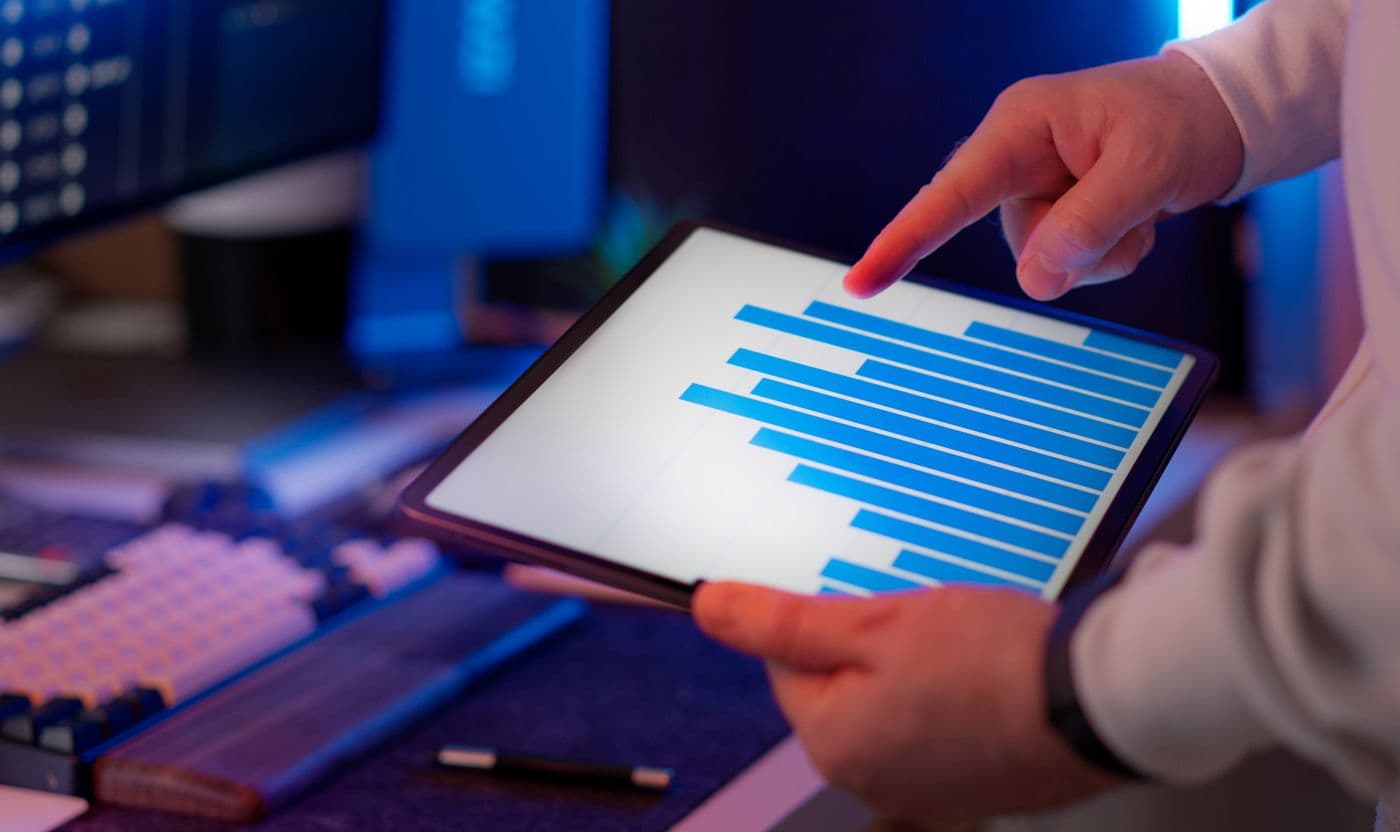 A hand points to a bar chart on a tablet screen.